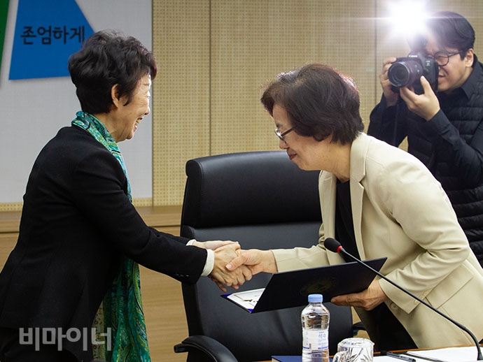 최영애 인권위원장(왼쪽)이 정강자 시민사회단체연대회의 공동대표(오른쪽)에게 위촉장을 수여하고 악수하는 모습.