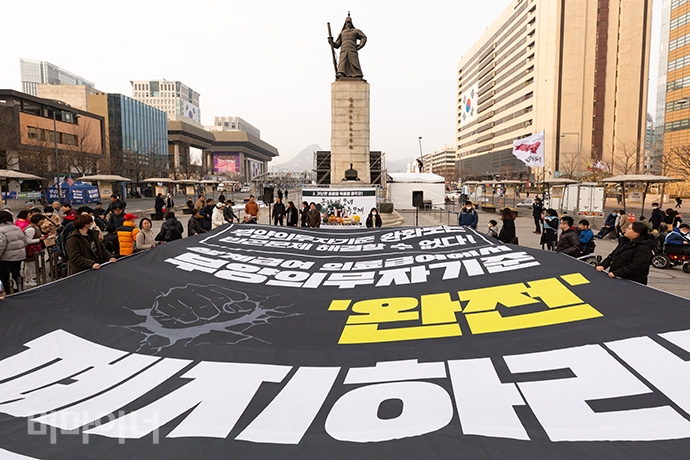 송파 세 모녀 사건 5주기 추모제가 28일 광화문광장 이순신 동상 앞에서 열렸다. “부양의무자 기준 완화로는 빈곤문제 해결할 수 없다. 생계급여·의료급여에서 부양의무자 기준 완전 폐지하라”라는 문구가 쓰인 대형 현수막이 펼쳐져 있다. 사진 박승원 기자. 