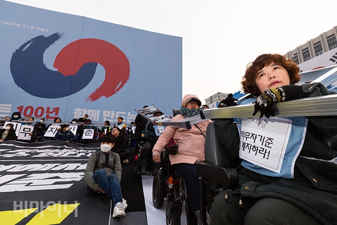 광화문광장에서 청와대로 행진하는 과정에서 장애인 활동가 100여명은 3·1운동 100주년을 기념하는 행사장 앞에서 ‘장애등급제·부양의무제·장애인 수용시설 진짜 폐지’를 촉구하며 한 시간가량 사다리를 몸에 걸고서 도로를 점거했다. 사진 박승원 기자.  