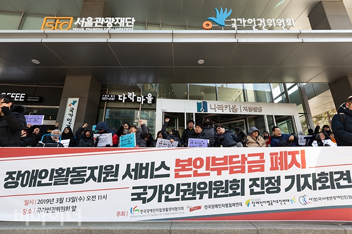 한국장애인자립생활센터협의회 등 4개 시민단체가 13일 오전 국가인권위원회 1층 로비 앞에서 ‘장애인활동지원 서비스 본인부담금 폐지 인권위 진정 기자회견’을 열었다. 271명의 진정인이 “활동지원 본인부담금 폐지하라”라고 외치고 있는 모습.