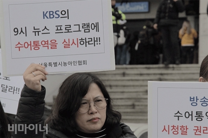 14일 KBS 본관 정문 앞에서 KBS 뉴스9에 수어통역방송을 요구하는 기자회견에 참석한 김태순 서울농아인협회 금천지부장이 ‘KBS의 9시 뉴스 프로그램에 수어통역을 실시하라!’라는 손팻말을 들고 있다.