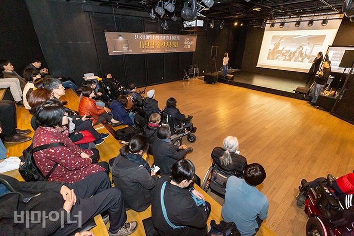 전국장애인차별철폐연대가 19일 오후 2시 서울시청 시민청 바스락홀에서 ‘전장연 10년 사진집 출간기념회’를 열었다. 전장연 활동가가 사람들에게 사진을 소개하고 있는 모습.
