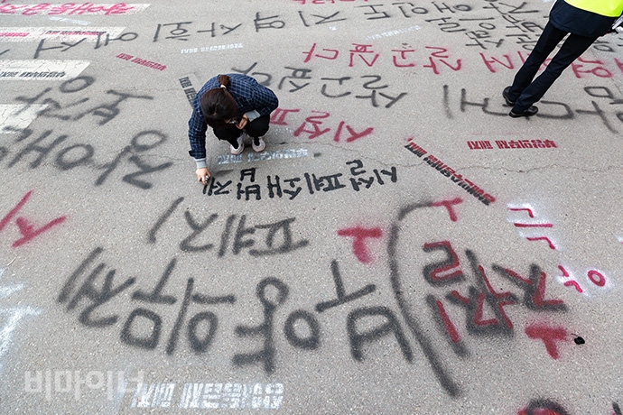 장애인활동가들이 기획재정부 건물 앞 도로에 ‘장애등급제 폐지’, ‘장애인수용시설 폐지’, ‘부양의무제 완전 폐지하라’ 등의 문구를 스프레이 라카로 새기고 있다. 사진 박승원