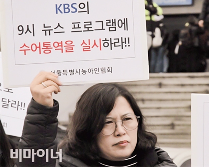 14일 KBS 본관 정문 앞에서 KBS 뉴스9에 수어통역방송을 요구하는 기자회견에 참석한 김태순 서울농아인협회 금천지부장이 ‘KBS의 9시 뉴스 프로그램에 수어통역을 실시하라!’라는 손팻말을 들고 있다. 사진 허현덕 3월 14일 KBS 본관 정문 앞에서 KBS 뉴스9에 수어통역방송을 요구하는 기자회견에 참석한 김태순 서울농아인협회 금천지부장이 ‘KBS의 9시 뉴스 프로그램에 수어통역을 실시하라!’라는 손팻말을 들고 있다. 사진 허현덕