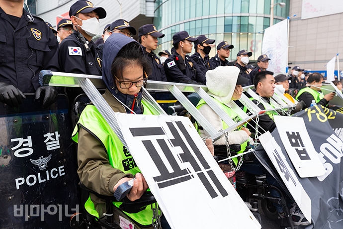 장애인 활동가들이 ‘장애인에 대한 억압’을 상징하는 사다리와 쇠사슬을 목에 걸고서 장애인이 처한 현실을 알리고 있다. 사진 박승원 장애인 활동가들이 ‘장애인에 대한 억압’을 상징하는 사다리와 쇠사슬을 목에 걸고서 장애인이 처한 현실을 알리고 있다. 사진 박승원