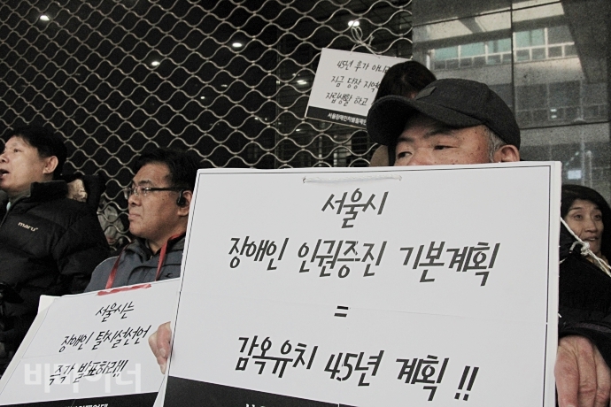 기자회견 참석자가 '서울시 장애인 인권증진 기본계획=감옥유치 45년 계획'이라는 손팻말을 들고 있다. 사진 최한별