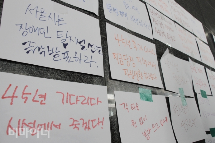 서울장차연 회원들이 대표단과 서울시의 면담 결과를 기다리며 시청 벽면에 '45년 기다리다 시설에서 죽겠다', '서울시는 장애인 탈시설 정책 즉각 발표하라!' 등의 문구를 써서 붙여놓았다. 사진 최한별