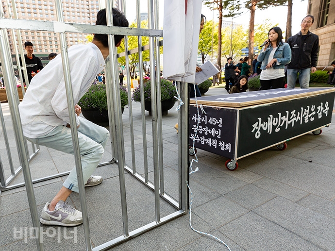 서울장애인차별철폐연대가 “제2기 서울시 장애인 인권증진 기본계획 내용을 전면 수정하라”면서 17일 오후 서울시청 정문 앞에서 결의대회를 열었다. 이들은 서울시 탈시설 계획은 “45년 중증장애인 감옥수감 계획에 불과하다. 감옥 같은 시설에 있다가 죽어서 나오는 경우가 현 서울시 탈시설 정책의 현주소”라고 꼬집으며 퍼포먼스를 벌였다. 사진 박승원