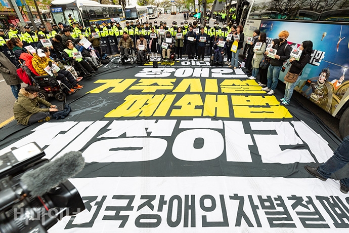 420장애인차별철폐공동투쟁단이 18일 ‘제39회 장애인의 날’ 기념식을 앞둔 오전 10시 “장애인을 차별하는 장애인의 날을 규탄한다”라며 63빌딩 앞 도로를 점거했다. “장애인 거주시설 폐쇄법 제정하라”고 적힌 대형 현수막을 펼친 채 ‘그들만의 행사’를 규탄했다. 사진 박승원