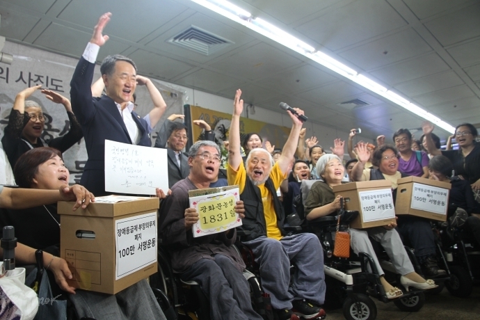 2017년 8월 25일, '3대적폐 폐지를 위한 광화문 농성장'을 찾은 박능후 장관과 농성단체 회원들이 함께 포즈를 취하고 있다. 이날 박 장관은 장애등급제, 장애인수용시설 정책과 더불어 부양의무자기준도 폐지하겠다고 약속했다. 사진 비마이너 DB