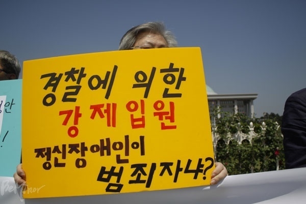 지난 2016년, 정신보건법 전부개정 추진 당시 경찰관도 정신병원에 입원 ‘요청’을 할 수 있는 신설 조항에 대해 한 활동가가 "경찰에 의한 강제입원, 정신장애인이 범죄자냐?"라고 쓰여진 피켓을 들고 반대하고 있는 모습.