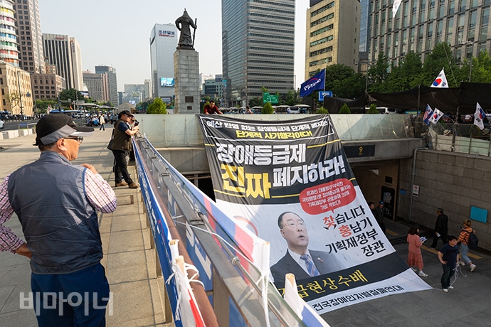 장애계가 장애등급제 ‘진짜’ 폐지를 위한 예산 확대를 요구하며 홍남기 기획재정부 장관을 ‘긴급 현상수배’하는 대형 현수막을 15일 세종문화회관 중앙 계단과 광화문 해치마당에 내걸었다. 사진 박승원