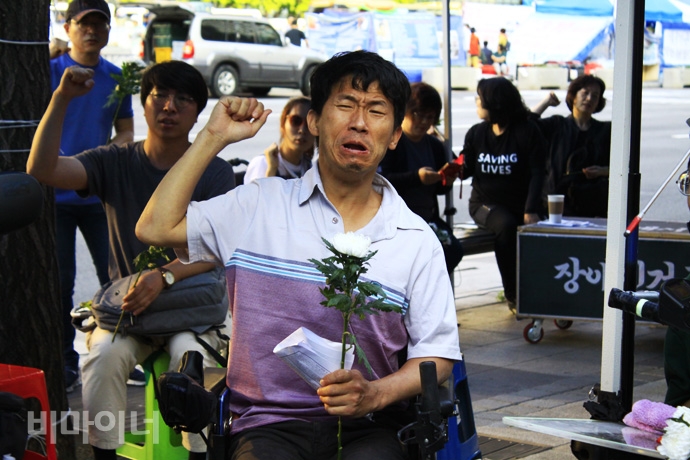 박동섭 민들레장애인자립생활센터 활동가가 한 손에는 국화꽃을 들고 투쟁의 결의를 다지고 있다. 사진 허현덕