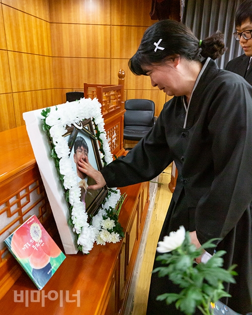 6월 23일에 열린 고 박정혁 활동가의 추모제. 유가족이 고인의 영정을 어루만지고 있다. 영정 사진 옆에는 고인의 글이 담긴 책이 놓여 있다. 사진 박정혁 6월 23일에 열린 고 박정혁 활동가의 추모제. 유가족이 고인의 영정을 어루만지고 있다. 영정 사진 옆에는 고인의 글이 담긴 책이 놓여 있다. 사진 박승원