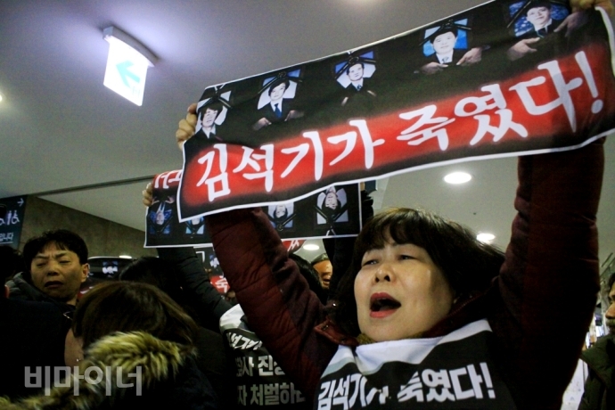 용산참사 10주기를 앞둔 지난 1월 15일, 용산참사로 남편 윤용현 씨를 잃은 유영숙 씨가 “김석기가 죽였다”라고 적힌 손팻말을 국회 안에서 들고 외치고 있다. 손팻말에는 용산참사 진압 당시 사망한 희생자 5명의 영정 사진이 담겨 있다. 사진 최한별 