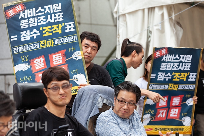 ‘서비스 지원 종합조사표=점수조작표’라고 적힌 피켓을 들고 있는 사람들. 사진 박승원 