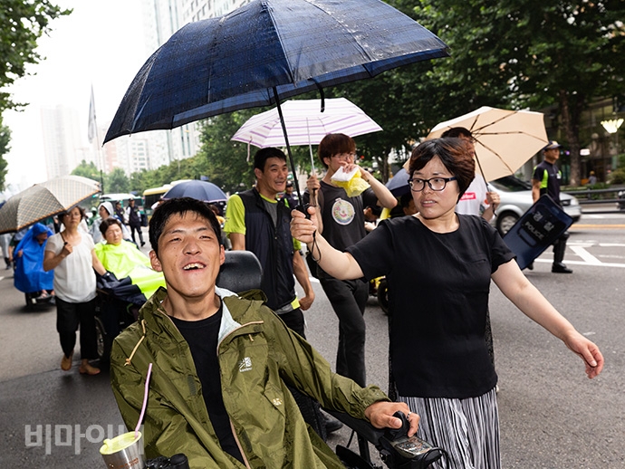 사회보장위원회에서 공덕오거리 방향으로 가는 길에 갑자기 비가 내리기 시작했다. 장애인 활동가들은 미리 준비해온 우산과 우비를 갖추고 행진을 이어갔다. 사진 박승원