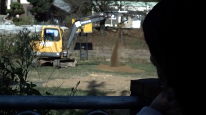 영화 ‘숨’의 한 장면: 수희가 시설의 담 밖에서 공사장을 바라보고 있다. 수희의 얼굴 옆면이 화면 오른쪽으로 보이고 공사장에는 포크레인과 흙이 보인다. 영화 ‘숨’의 한 장면: 수희가 시설의 담 밖에서 공사장을 바라보고 있다. 수희의 얼굴 옆면이 화면 오른쪽으로 보이고 공사장에는 포크레인과 흙이 보인다.