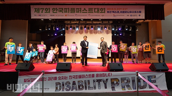 발달장애인 13명과 박인영 부산시부시장과 안형필 한국피플퍼스트대회 위원장이 ‘부산시발달장애인권리보장선언문’을 낭독한 후 한 글자씩 쓰인 프래카드를 들고 퍼포먼스를 펴칠고 있다. 사진 박승원 발달장애인 13명과 변성완 부산시 행정부시장과 안형필 부산피플퍼스트 위원장이 ‘부산시발달장애인권리보장선언문’을 낭독한 후 한 글자씩 쓰인 프래카드를 들고 퍼포먼스를 하고 있다. 사진 박승원