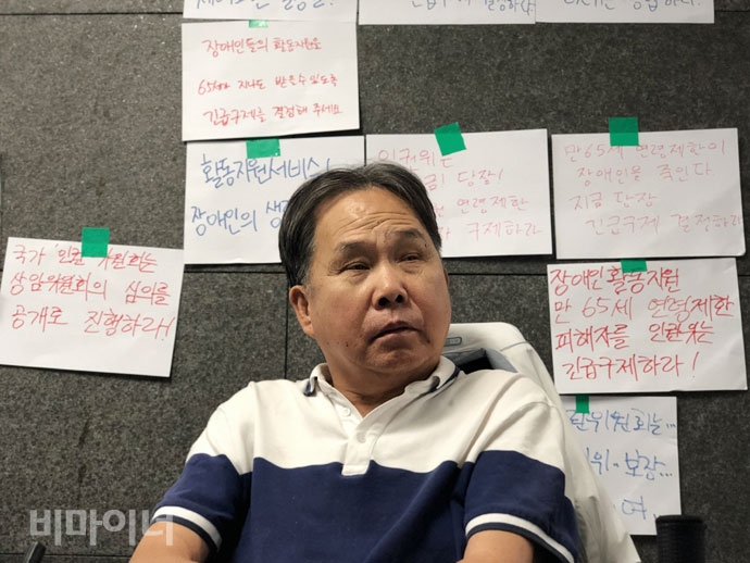 국가인권위원회가 활동지원 만 65세 연령제한 문제에 대해 긴급구제 결정을 내렸다. 인권위 상임위원회 회의 전, 회의실 앞에서 피케팅을 하는 송용헌 씨. 그의 뒤로 “장애인활동지원 만 65세 연령제한 피해자를 인권위는 긴급구제하라!”등의 글이 적힌 종이들이 붙어있다. 사진 강혜민