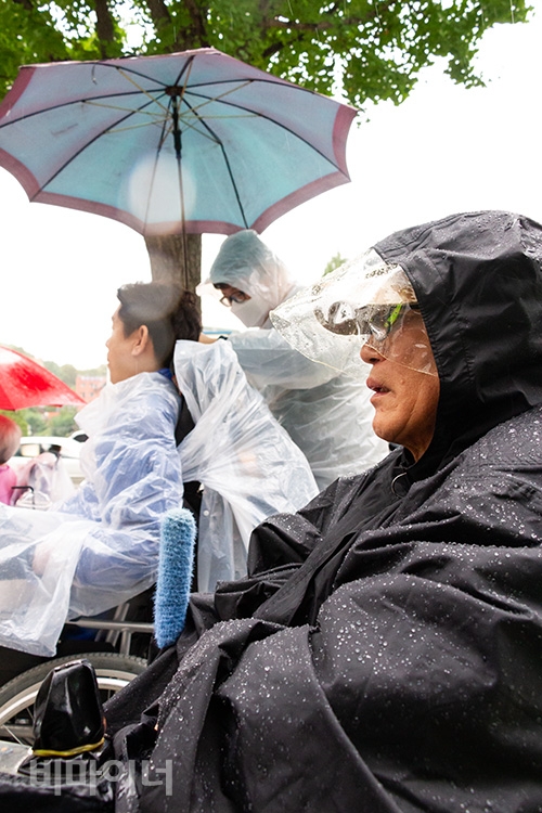우비를 입은 한 참가자가 발언을 듣고 있는 모습. 사진 박승원 우비를 입은 한 참가자가 발언을 듣고 있는 모습. 사진 박승원