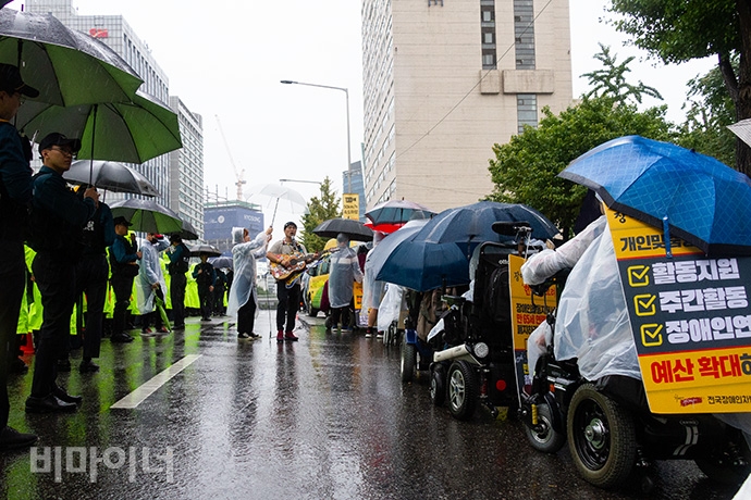 박준 노동가수가 서울시청으로 행진하는 장애계를 위해 노래로 연대했다. 사진 박승원 박준 노동가수가 서울시청으로 행진하는 장애계를 위해 노래로 연대했다. 사진 박승원