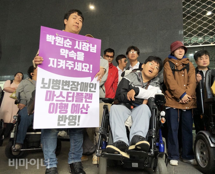 장애인 활동가가 “박원순 시장님, 약속을 지켜주세요. 뇌병변장애인 마스터플랜 이행 예산 반영!”이라고 적힌 피켓을 들고 있다. 사진 강혜민