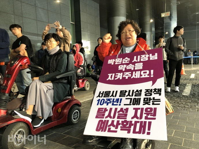 장애인 활동가가 “서울시 탈시설정책 10주년! 그에 맞는 탈시설 지원 예산 확대!” 피켓을 들고 있다. 사진 강혜민