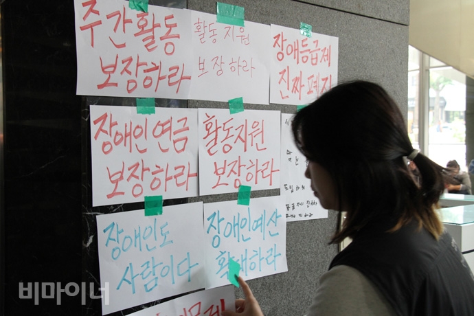 22일, 장애인들이 오전 나라키움저동빌딩(서울 중구 삼일대로 340) 국가인권위원회 1층에 농성장을 꾸리고 내년 장애인 복지 예산 확대를 촉구하며 농성에 돌입했다. 전장연 활동가가 엘리베이터 앞에 장애인과 가난한 사람들의 바람을 담은 글귀를 붙이고 있다. 사진 허현덕