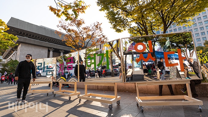 26일, 광화문광장 옆 세종로공원 입구에 커다란 거울이 세워져 있고 그 위에 “우리는 지금 여기에 있다”라는 문구가 적혀 있다. 사진 박승원 