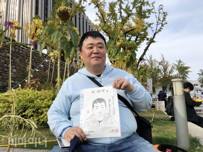 매드프라이드에 참여한 정현석 씨가 이동수 화백이 그린 자신의 캐리커처를 들고 있다. 사진 강혜민 