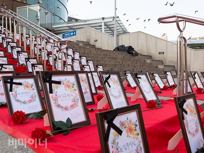 서울역 광장 앞 계단에 홈리스 추모공간 ‘홈리스 기억의 계단’이 펼쳐져 있고 그 뒤로 홈리스 한 명이 계단에 누워 있다. 서울역 광장 앞 계단에 홈리스 추모공간 ‘홈리스 기억의 계단’이 펼쳐져 있고 그 뒤로 홈리스 한 명이 계단에 누워 있다. 사진 박승원