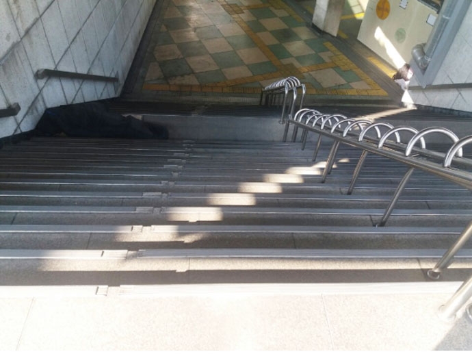 김기성 님이 돌아가신 서울역 우체국 앞 지하도 계단. 한 노숙인이 위태롭게 잠을 청하고 있다. 아래에는 노숙인 응급대피소가 있지만, 휠체어를 타고 내려갈 방법은 없다. 사진 종교계노숙인지원민관협력네트워크