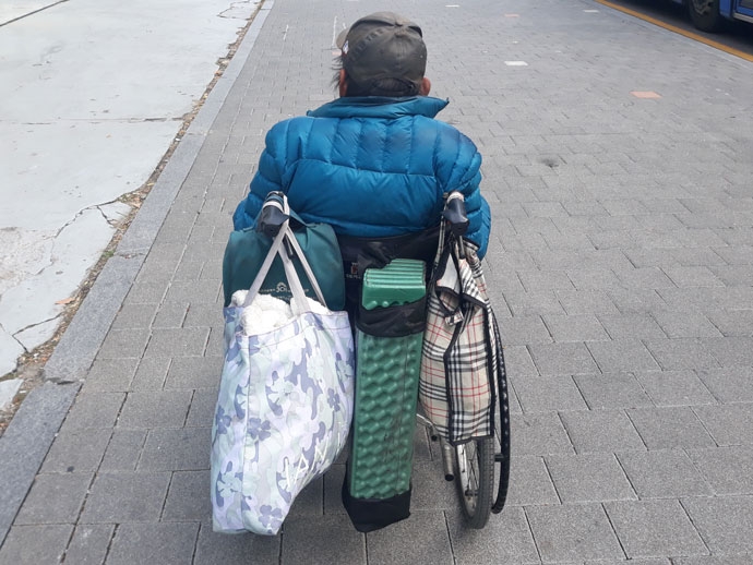 진수 님의 휠체어 손잡이에는 바닥에 까는 깔개와 무릎담요가 걸려 있다. 이 물건들로 한겨울 추위를 견뎌야 한다. 사진 종교계노숙인지원민관협력네트워크