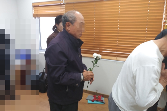 생전에 가족처럼 고인을 돌보던 지인이 무연고 사망자 장례식에서 헌화하고 있습니다