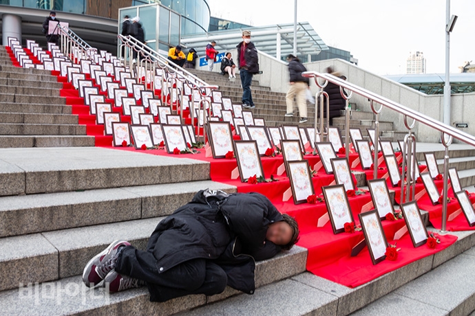 이 아무개 씨가 ‘홈리스 기억의 계단’ 옆에 앉아있다가 곤히 잠들었다. 그가 입은 검은 롱패딩은 찢어진 부분을 꿰매기 위해 바늘과 실 대신 호치키스와 철사 침으로 대신했다. 동료에 따르면 식당가가 많은 서울역 14번 출구 일대에서 술을 즐겨 마신다. 사진 박승원