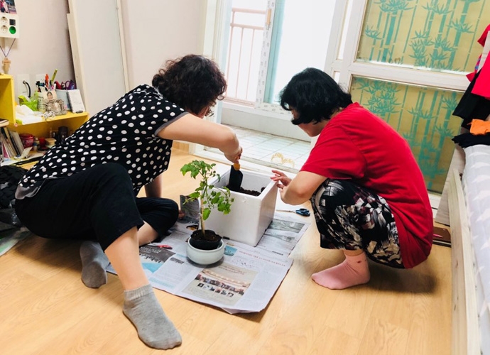 발달장애인이 주거코치와 함께 화분에 나무를 심고 있는 모습. 사진 충현복지관