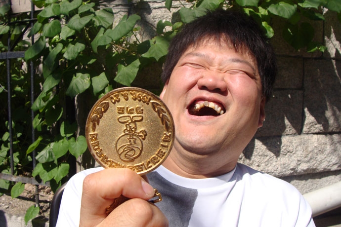 2010년 9월, 우동민 열사가 과거 ‘경기도 장애인 체육대회’에서 받은 메달을 보이며 웃고 있다. 사진 장애해방열사_단