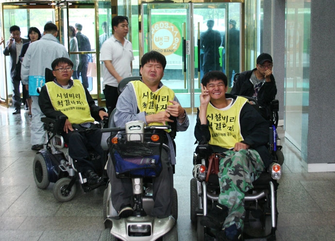 2008년 6월, 동료들과 시설 비리 척결 투쟁에 나선 우동민 열사. 앞줄에 스쿠터 탄 사람이 우동민 열사. 사진 장애해방열사_단