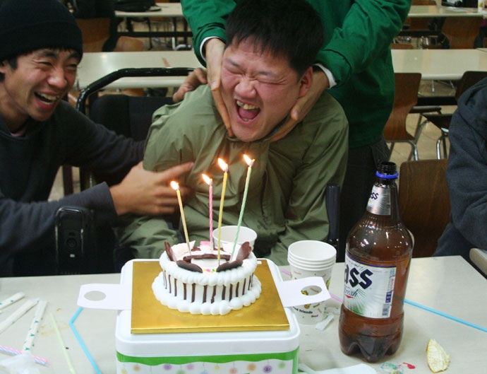 2009년 10월 24일, 우동민 열사 생일날 동료 활동가들과. 우동민 열사 앞에 초가 꽂힌 케이크와 맥주가 놓여 있다. 사진 장애해방열사_단