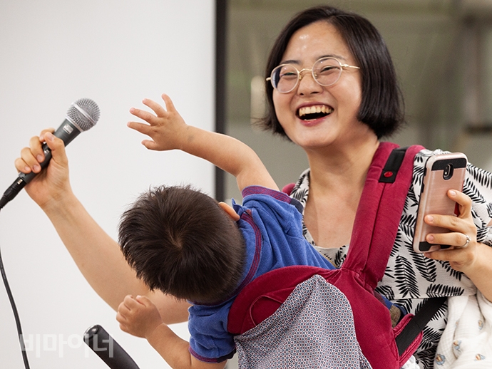 진유경 정치하는엄마들 활동가가 발언하는 모습. 진 활동가에게 업힌 아기가 마이크에 관심을 보이자 진 활동가는 이를 막으며 크게 웃음 지어 보였다. 사진 박승원