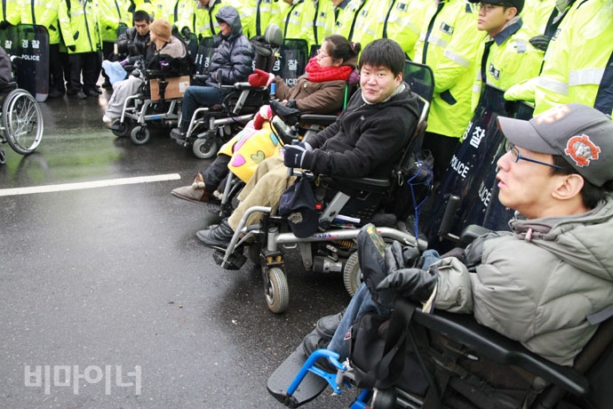 2010년 12월 8일, ‘한나라당의 장애인활동지원법 날치기 통과’를 규탄하는 기자회견 후 도로점거를 하며 항의하는 장애인활동가들. 경찰과 대치하고 있는 우동민 열사. 