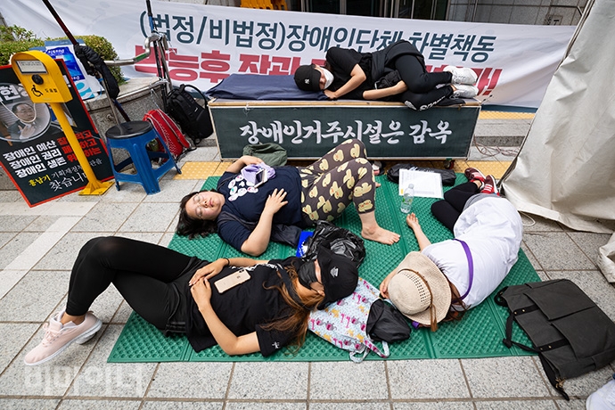 사회보장위원회 앞에서 노숙농성을 펼친 장애인 활동가들은 2일 오전 10시부터 ‘법정∙비법정 장애단체 차별책동 박능후 장관 공개사과’ 기자회견을 열었다. 기자회견을 마친 조은별 김포장애인자립생활센터 활동가를 비롯한 장애인 활동가들이 지쳐 잠들어 있다. 사진 박승원