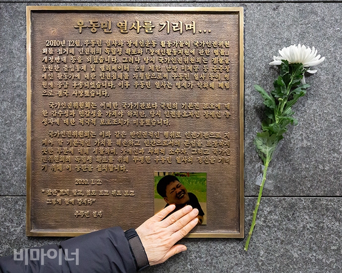 권순자 씨가 고 우동민 활동가의 동판을 어루만지고 있다. 사진 박승원