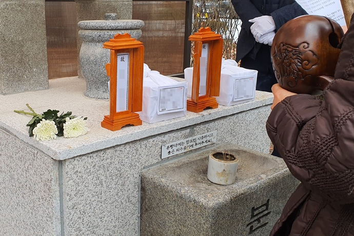 비극적인 죽음을 선택한 아들 그리고 어머니. 무연고 사망자가 된 모자의 유골함 앞에서 종교단체의 추모의식이 진행되고 있다. 사진 나눔과 나눔