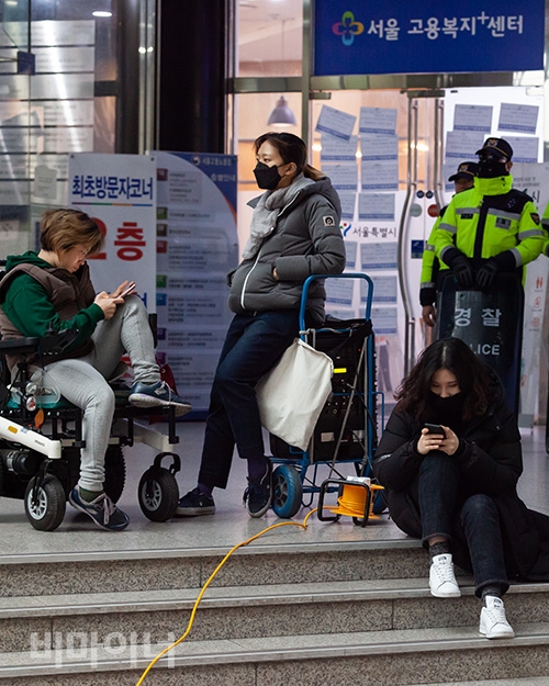 여성 활동가들이 경찰과 안전관리 직원에게 확성기를 뺏기지 않기 위해 자리를 지키고 있다. 그 뒤로는 ‘서울 고용복지 센터’라고 적힌 입구가 보인다. 사진 박승원