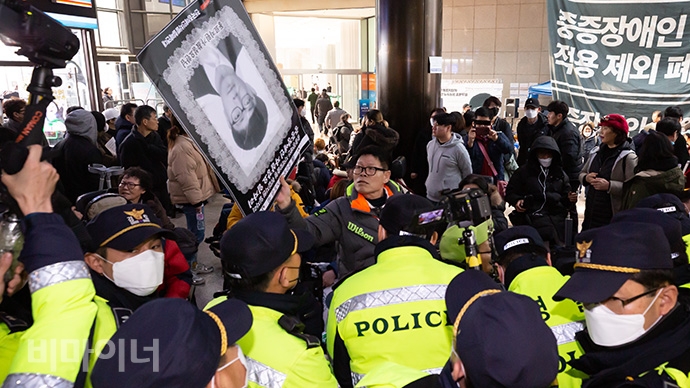 한 장애인 활동가가 경찰 채증에 저항하며 손팻말로 경찰이 든 카메라를 가리고 있다. 사진 박승원