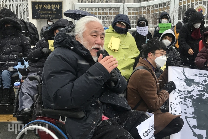 박경석 노들장애인야학협의회 이사장은 현재 감염병 재난 상황에 정부가 즉각 대책을 마련해야 한다고 촉구했다. 사진 허현덕 박경석 전국장애인야학협의회 이사장은 현재 감염병 재난 상황에 정부가 중증장애인의 안전대책을 즉각 마련해야 한다고 촉구했다. 기자회견 참가자들의 옷에는 눈이 쌓여 있다. 사진 허현덕