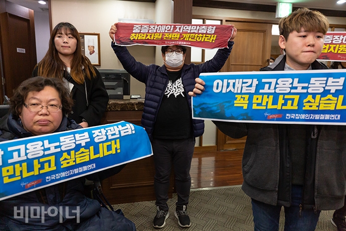 장애인활동가들이 이재갑 장관이 참여하는 ‘2020년 제1차 청년고용촉진특별위원회’ 회의에 기습적으로 들어가 면담을 요청하고 있다. 이들의 손에는 ‘이재갑 고용노동부 장관님! 꼭 만나고 싶습니다!’ ‘중증장애인 지역맞춤형 취업지원 전면 개편하라’라고 적힌 손팻말이 들려있다. 사진 박승원