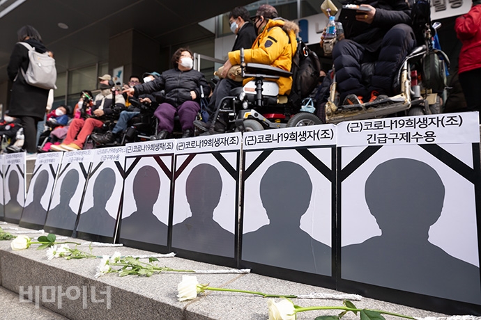 코로나19 사망자를 애도하는 얼굴 없는 영정사진 11개가 국가인권위원회 계단에 놓여있다. 그 앞에는 국화꽃 한 송이씩 놓여있다. 사진 박승원